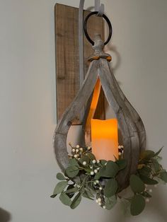 a candle is lit in a hanging lantern with greenery and berries on the table