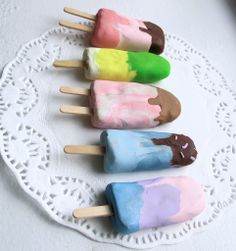 four ice cream pops are on a white doily