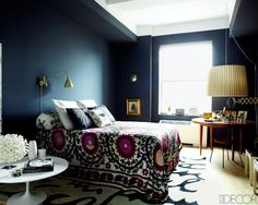 a bedroom with dark blue walls, white furniture and an area rug on the floor