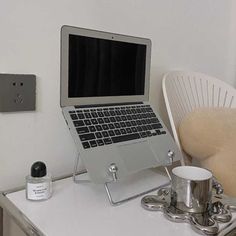 an open laptop computer sitting on top of a white desk next to a cup and saucer