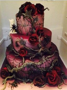 a three tiered cake with red roses and spider webs on the bottom layer