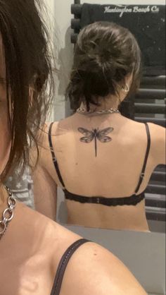 a woman with a dragonfly tattoo on her back is taking a selfie in the mirror