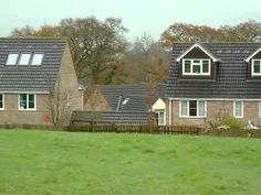 a couple of houses sitting on top of a lush green field