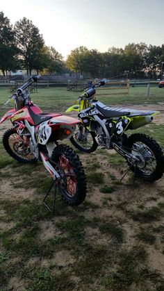 two dirt bikes are parked in the grass