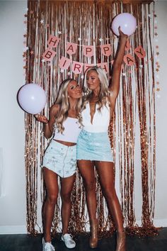 two beautiful young women standing next to each other in front of a happy new year sign