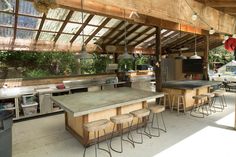 an outdoor kitchen with lots of counter space and stools around the island, as well as several lights hanging from the ceiling