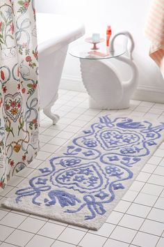 a bathroom with a bathtub, toilet and rug on the floor in front of it