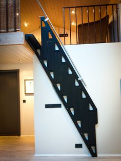 a black stair case next to a white wall