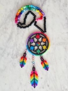 a multicolored beaded dream catcher is laying on the snow with beads around it