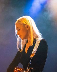 a woman with blonde hair playing an electric guitar