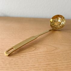 a golden spoon with a gold handle on a wooden table