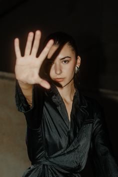 a woman in a black dress is holding her hand up to the camera with both hands