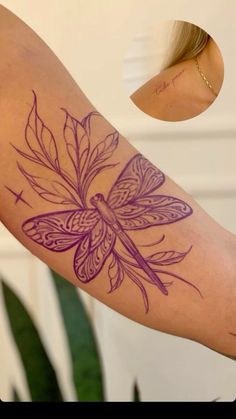 a woman's arm with a dragon tattoo on it and a plant behind her