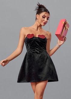 Elevate your date night look with our Red Heart Detail Velvet Mini Dress. The rich black velvet fabric will make you stand out, while the flared silhouette adds a touch of femininity. Its strapless design and delicate heart detailing bring a romantic touch to your outfit. Perfect for a hot date or any special occasion. Fabric: Non-Stretch Material: Polyester Fiber Valentine's Day Party Dress With Sweetheart Neckline, Black Sleeveless Velvet Party Dress, Flirty Mini Dress With Heart-shaped Neckline For Evening, Black Velvet Dress For Date Night, Valentine's Day Party Dress Mini Length, Evening Velvet Dress With Sweetheart Neckline, Strapless Velvet Mini Dress For Party, Date Night Corset Dress With Heart-shaped Neckline, Party Velvet Dress With Sweetheart Neckline