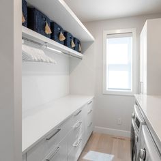 a white laundry room with lots of cabinets and drawers next to a washer and dryer