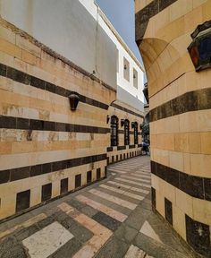 an alley way with two buildings on either side and one building in the middle that has black and white striped walls