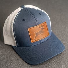 Stylish leather patch hats with Deer Stamp, personalization, or logo! SPECS *Leather Patch Color Options: Natural Dublin, Nut Brown Dublin, or Cafe Chromexcel *Hat Color Options: Choose from Navy/White, Charcoal, or Green/Khaki *All of our products are made to order by hand in McKinney, TX MATERIALS *REAL HORWEEN LEATHER: Premium Full-Grain Leather. oEach patch is one-of-a-kind and made from part of a whole hide of leather. There will be unique variation from item to item that truly makes it you Casual Brown Leather Trucker Hat, Outdoor Leather Baseball Cap With Leather Patch, Adjustable Trucker Hat With Leather Backing And Curved Brim, Leather Baseball Cap For Outdoor Activities, Adjustable Leather-backed Trucker Hat With Curved Brim, Leather Flat Brim Baseball Cap For Outdoor, Adjustable Leather Trucker Hat, Casual Leather Hats With Sweatband, Leather Snapback Baseball Cap