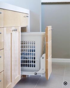 an open cabinet door in the middle of a kitchen with white tile flooring and wooden cabinets