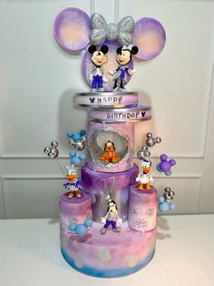 a birthday cake with mickey mouse figurines on top