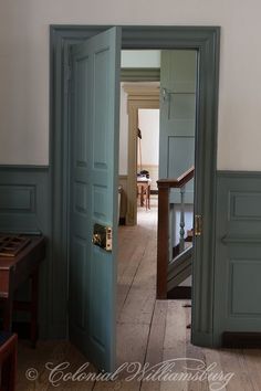 an open door leading to another room with wood floors and green painted walls in the background