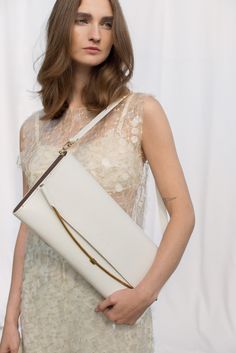 A white, elongated bag to be worn on the shoulder or for clutch-style carrying. Inside, there is an open compartment finished with viscose lining and a flat, elongated pocket on the back side of the bag that can be zipped shut. The clasp is handmade from brass according to our original design. The sides of the bag are made of pine wood, veneered with American walnut. There is an embossed logo on the front. Dimensions: 40 x 18 x 3 cm Included strap: 68 x 2 cm The body of the bag is made of the hi Elegant Envelope Box Bag For Daily Use, White Handheld Baguette Bag For Evening, Cream Rectangular Baguette Bag For Evening, Rectangular Cream Baguette Bag For Evening, Cream Rectangular Evening Baguette Bag, White Clutch With Detachable Handle For Daily Use, White Clutch With Detachable Handle, White Clutch With Detachable Handle As Shoulder Bag, White Leather Elegant Clutch