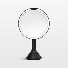 a round mirror sitting on top of a black stand