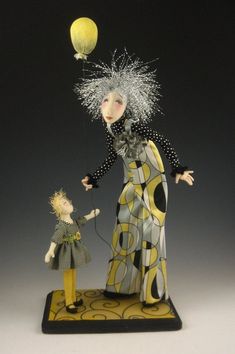 a figurine is holding the string of a balloon while a doll stands next to it