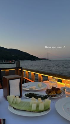 there is a table with plates and food on it that has water in the background