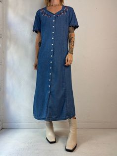 "- Vintage Wardrobe Essentials button up denim dress - Floral embroidery details - Ruffle trim on the sleeves - 100% cotton - Made in China - Tagged 12   Bust: 20.5\" Waist: 19\" Length: 49\"" Button-up Denim Blue Cotton Dress, Denim Blue Cotton Button-up Dress, Button-up Cotton Denim Dress With Pockets, Button-up Denim Dress With Pockets, Cotton Button-up Denim Dress With Pockets, Cotton Denim Midi Dress With Buttons, Denim Blue Cotton Dress With Buttons, Fitted Button-up Denim Dress With Button Cuffs, Cotton Denim Button-up Dress For Daywear