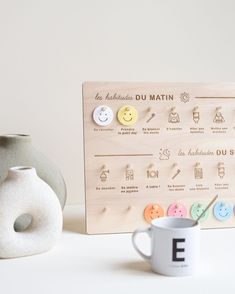 a coffee cup next to a wooden board with buttons on it and a ceramic vase