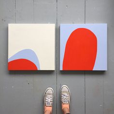 a person standing in front of two paintings on the ground with their feet propped up