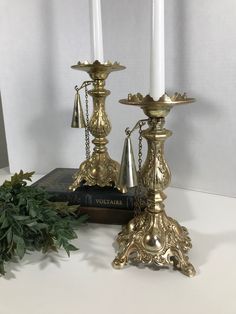 two brass candlesticks sitting on top of a book