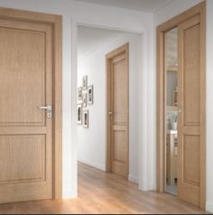 an empty room with two wooden doors and pictures on the wall behind them, along with hardwood flooring