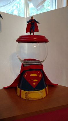 a glass bowl with a superman figure on top of it and a red object in the middle