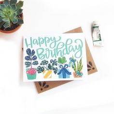 a happy birthday card sitting on top of a table next to a potted plant