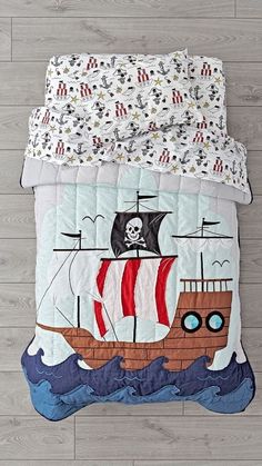 a bed with a pirate ship quilt on it's cover and pillowcases