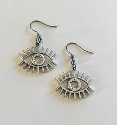 Evil eye earrings, silver eye earrings, ancient Egyptian/ Greek protection from the evil eye earrings, detailed eye charms. STAINLESS STEEL ear wires fish hooks jewelry. Egypt god Horus, for that witchy woman, Wicca Wiccan Witch. Occult esoteric occultism *earring wires measure approx .6 of an inch, or just over half an inch *charm itself approx .8 of an inch, (or just over half an inch) *STAINLESS STEEL earring wires fish hooks *charms are silver alloy *comes in a gift box earrings eye evileye Silver Metal Evil Eye Jewelry, Metal Dangle Earrings With Evil Eye, Evil Eye Symbolic Metal Jewelry, Symbolic Evil Eye Metal Jewelry, Silver Metal Jewelry With Evil Eye, Symbolic Eye-shaped Silver Jewelry, Fish Hook Jewelry, God Horus, Wiccan Witch