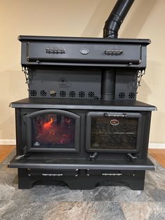 a black stove top oven sitting on top of a wooden floor next to a wall