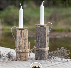 two white candles are sitting on some wood