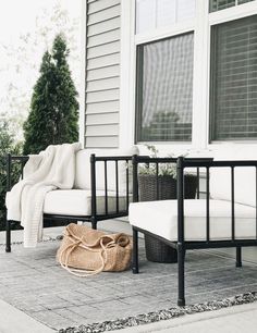 a white couch sitting on top of a patio next to a chair and table with a bag