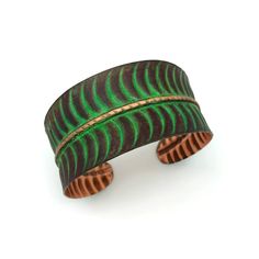 a green and brown cuff bracelet on a white background