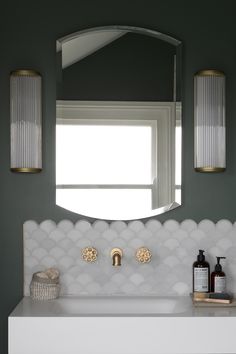 a bathroom sink under a large mirror next to a window with two lights on it