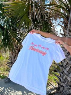 Our EXCLUSIVE Sunhoney Retro Palm Tee screams summer vibes with its playful graphic of pink palm trees and orange retro design. Featuring our classic logo in a stunning orange and pink colorway, this tee is the perfect addition to your warm weather wardrobe. This summer graphic is printed on Comfort Colors tee and is full lenght, shirt is tucked in for photos for styling purposes. Get yours now and be prepared to wear all summer long! Designed by us, handmade by us in Jacksonville Beach, FL Prod Pink Cotton Top With Palm Tree Print, Orange Graphic Print T-shirt For Summer, Pink Palm Tree Print Short Sleeve Top, Tropical Palm Tree Print T-shirt For Spring, Spring Tropical T-shirt With Palm Tree Print, Spring Crew Neck T-shirt With Palm Tree Print, Pink Tropical T-shirt For Summer, Summer Graphic Tee With Palm Tree Print, Spring Palm Tree Print Short Sleeve T-shirt