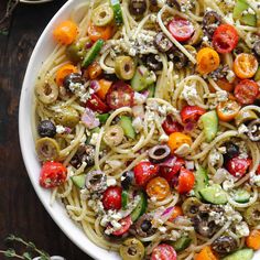 a white bowl filled with pasta and veggies on top of a wooden table