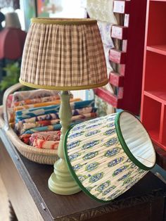 a lamp sitting on top of a table next to a basket filled with cloths