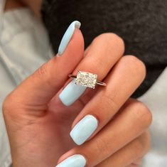 a woman's hand with light blue nails and a diamond ring on her finger