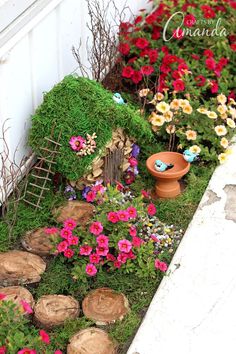 a small garden with flowers and plants in the ground next to a house made out of logs