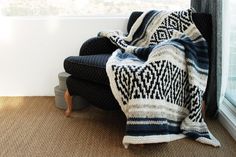 a black and white blanket sitting on top of a chair next to a window