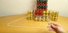 a person is stringing up christmas ornaments on a table with gold and red balls in the background