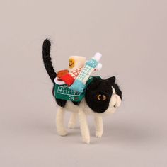 a black and white cat with toothbrushes in it's mouth, on a gray background